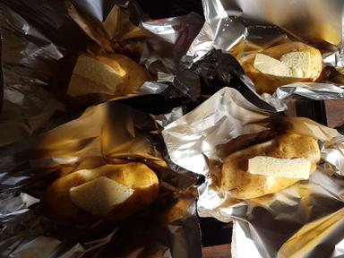 Baking potatoes with a pat of butter in foil. Ready to be wrapped up and placed in the oven.