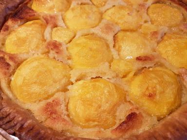 A freshly baked tart with home grown peaches embedded in frangipane