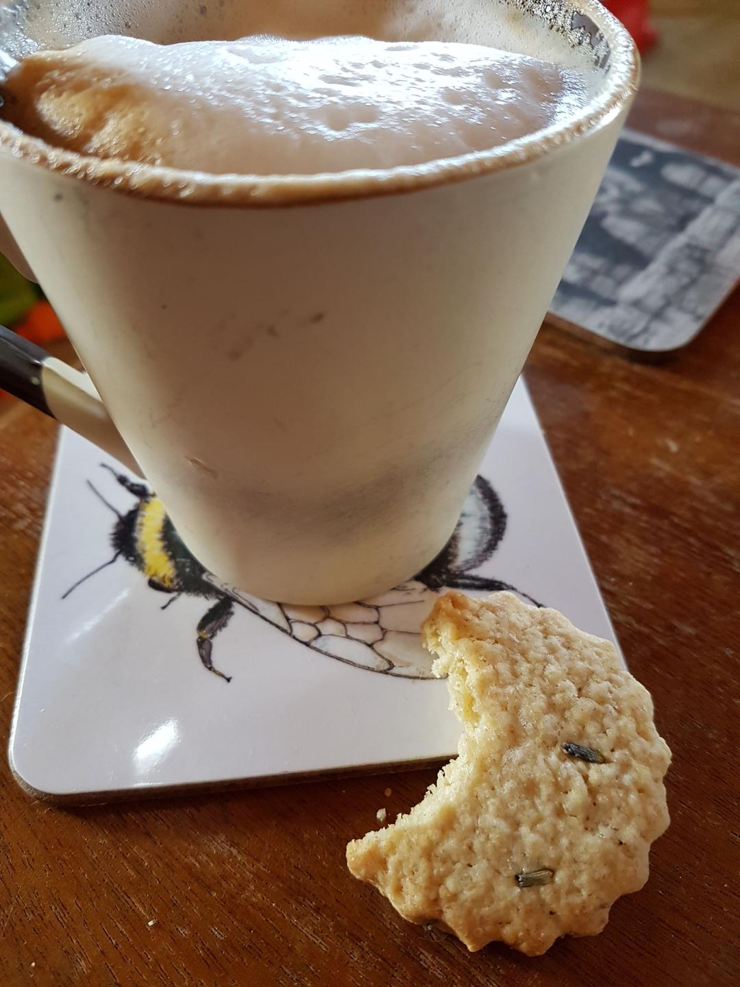 A lavender biscuit accompanying a cup of coffee. As usual the photographer couldn't wait to take a bite!